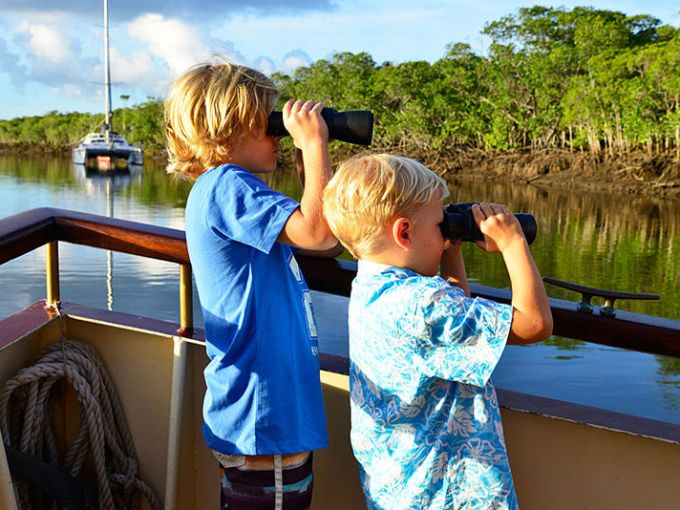 a young boy standing in front of a body of water