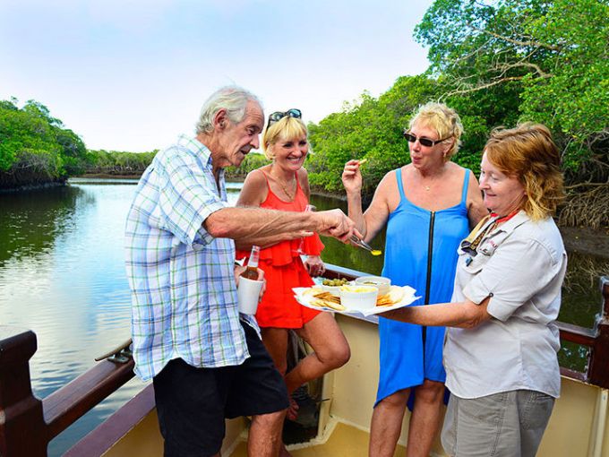 a group of people are drinking from a lake